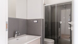 A modern bathroom with a bathtub, toilet, and glass-enclosed shower area. - Cozy Studio in the heart of Navigli (Milano)