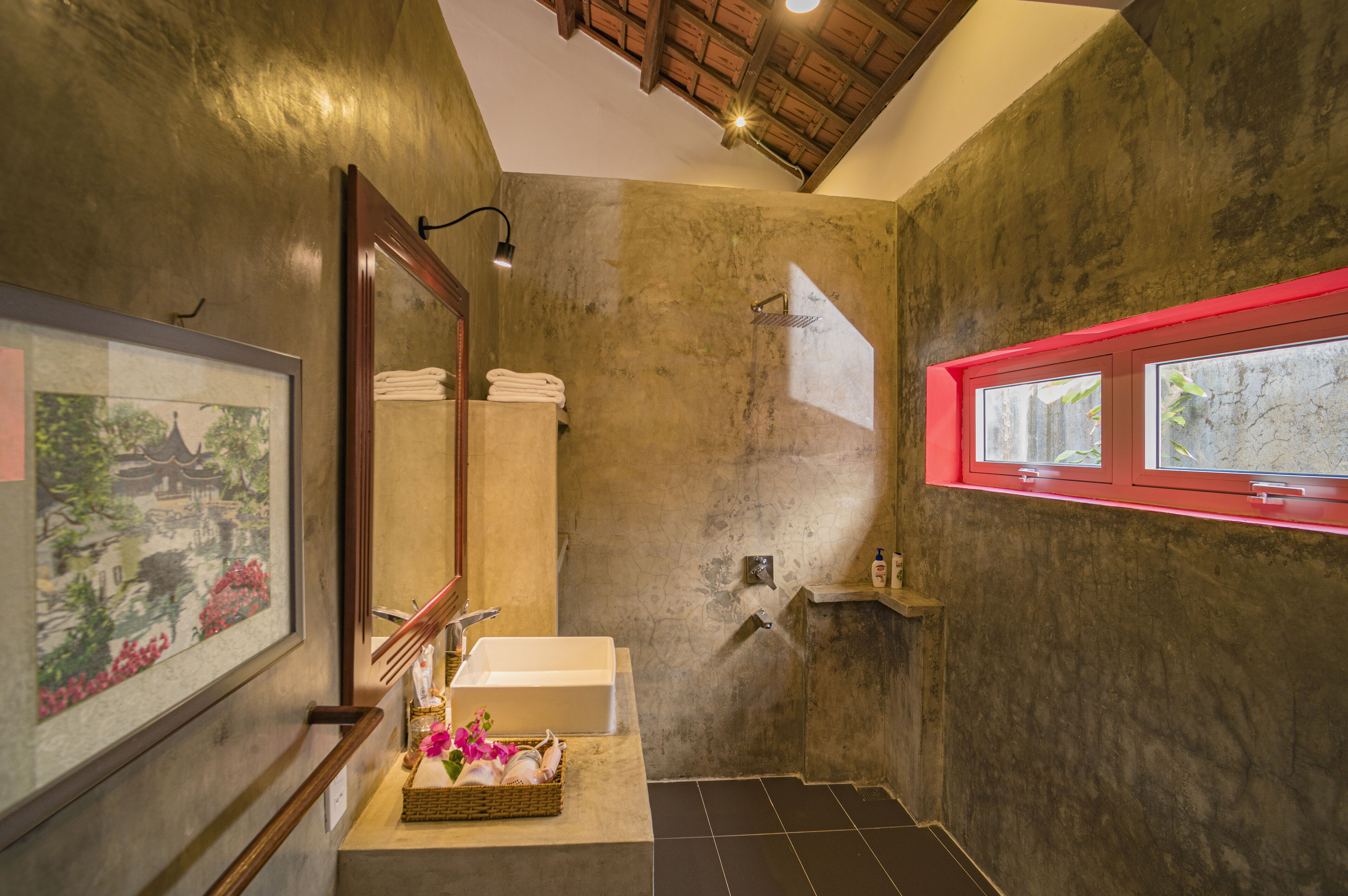 A bathroom with a large mirror, a bathtub, and a window with a red frame.