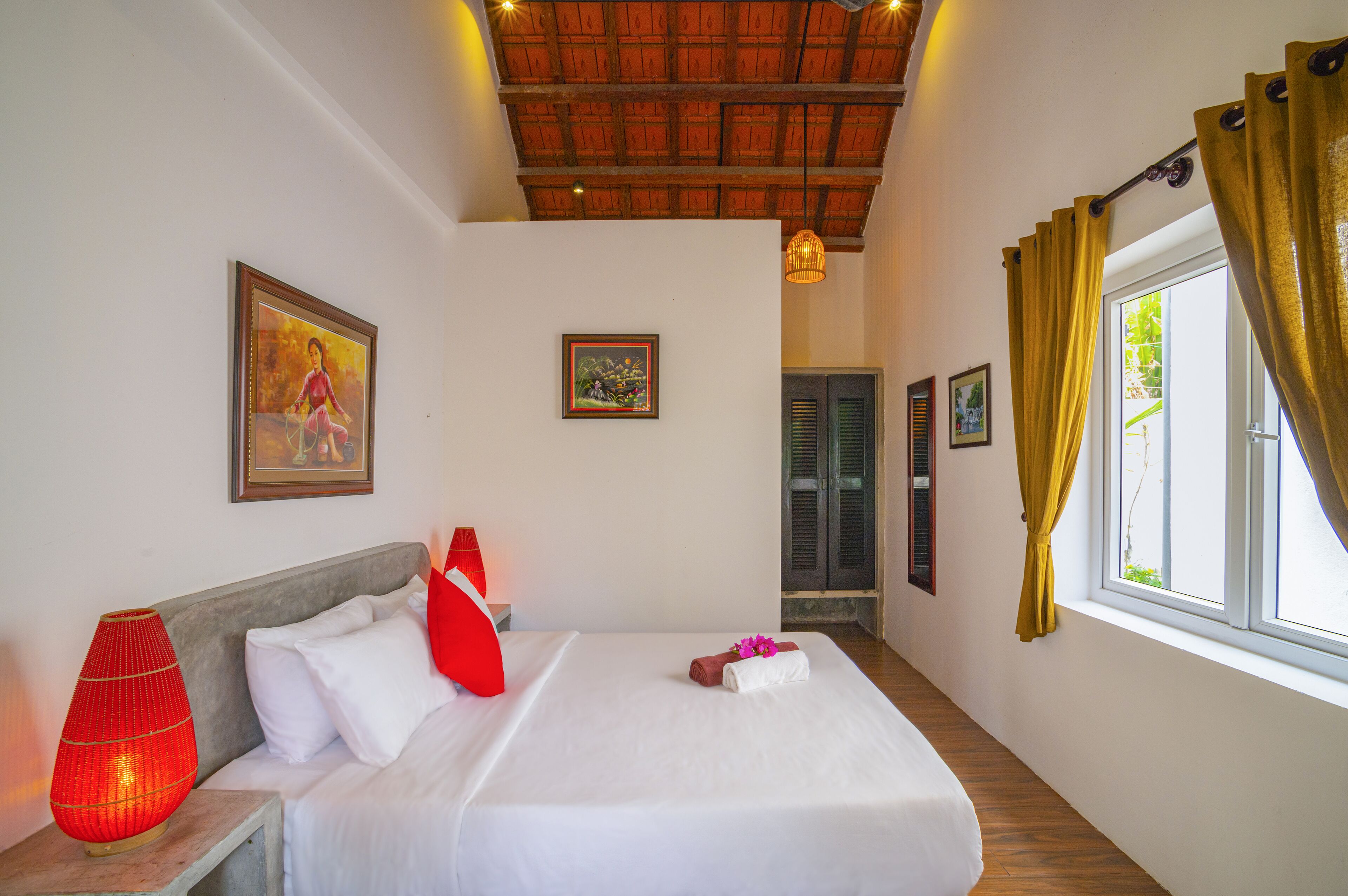 Une chambre d’hôtel avec un lit, une lampe rouge et une fenêtre avec des rideaux.