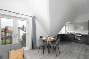 A modern apartment with a dining area, kitchen, and balcony. - Skyvillion Apartments - Vineyard Enfield Chase - 1Bed Apartment  (Greater London)