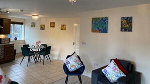 A dining area with a chandelier, a table with chairs, and artwork on the walls. - Exquisite Modern Homely Flat (Cambridge)