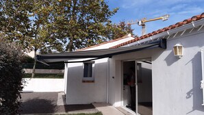 A white building with a tiled roof, a covered patio, and a visible construction crane in the background. - Charming house with garden in Sables-d'Olonne (Les Sables-d'Olonne)