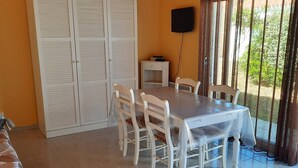 A dining area with a table and chairs, a ceiling fan, a TV, and a view of greenery outside. - Charming house with garden in Sables-d'Olonne (Les Sables-d'Olonne)