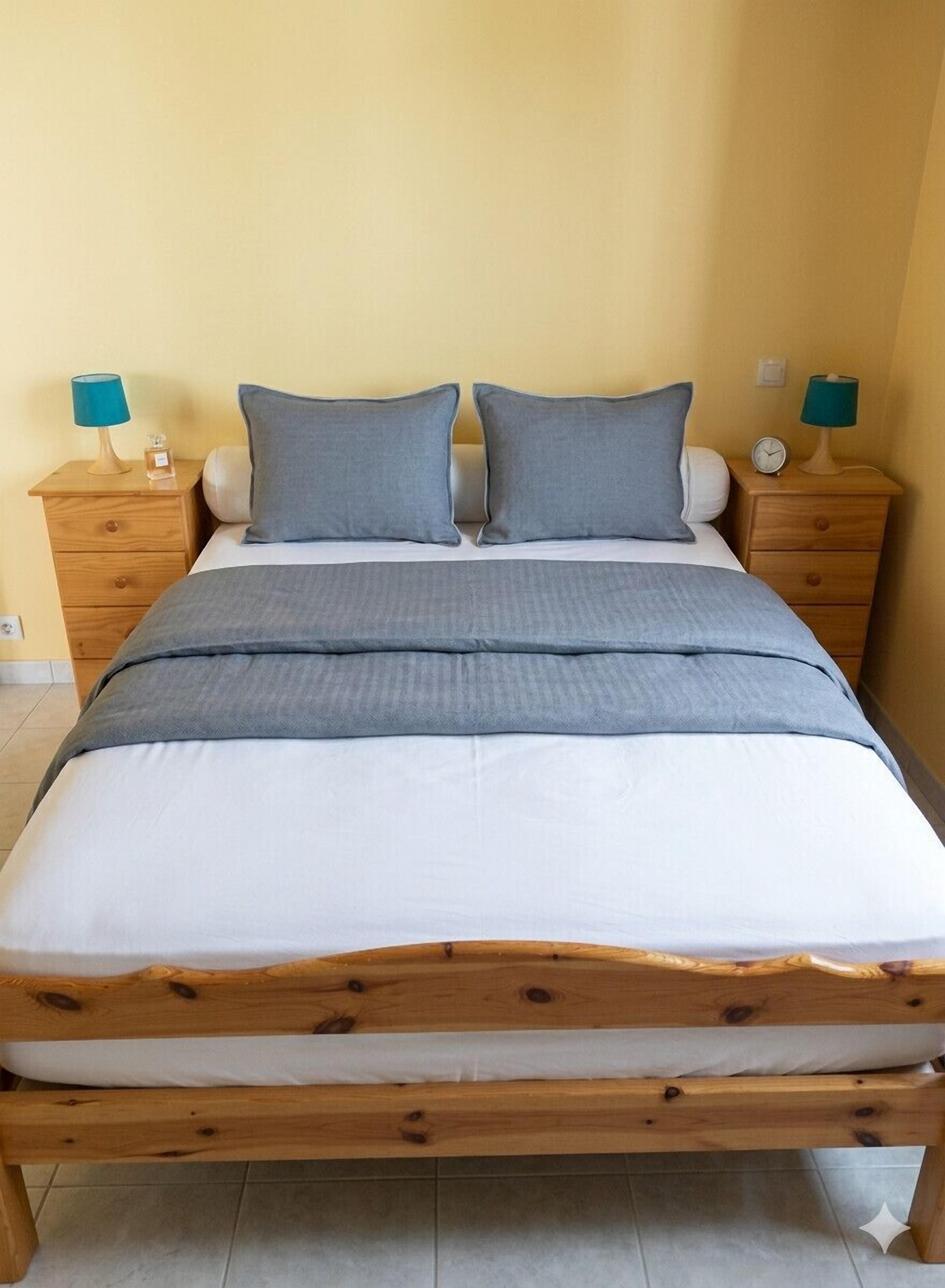 A bed with a wooden frame, two nightstands, and two lamps.
