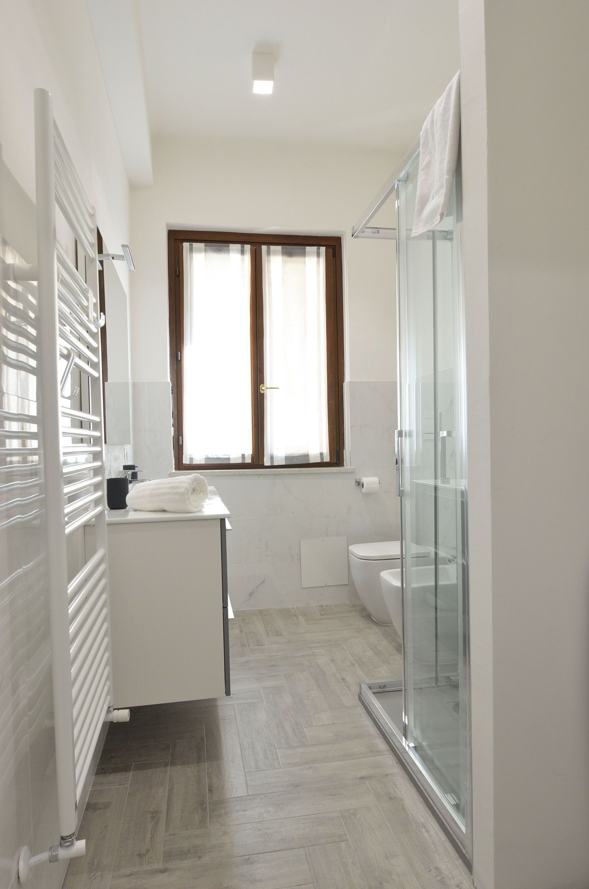 Ein modernes Badezimmer mit Duschkabine aus Glas, Toilette und Waschbecken mit Handtuch.