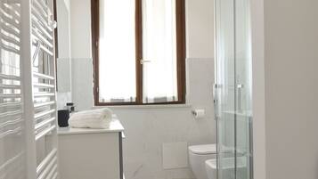 Ein modernes Badezimmer mit Duschkabine aus Glas, Toilette und Waschbecken mit Handtuch.
