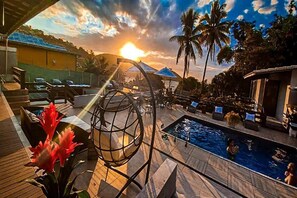 A poolside area with lounge chairs, a pool, and a sunset view. - Bliss Hoteis Jaoa Fernandes (Búzios)