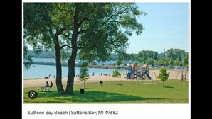 A park with a playground, picnic tables, and a view of the water.