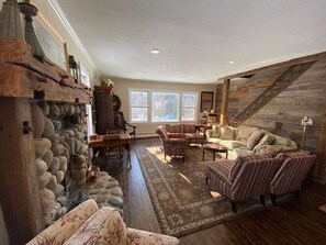 Relax in a warm living space with a stone wall, comfortable seating area, and a wooden staircase.