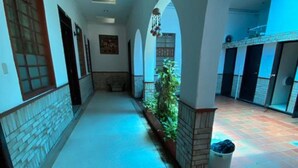 A corridor with arches, a potted plant, and a trash bin. - Selecta Colonial (Villavicencio)