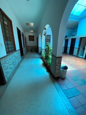 A corridor with arches, a potted plant, and a trash bin. - Selecta Colonial (Villavicencio)