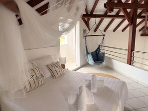 A bedroom with a bed, a hanging chair, and a view of the outdoors. - Villa Happy - Le Gosier, Villa Happy - Le Gosier (Le Gosier)