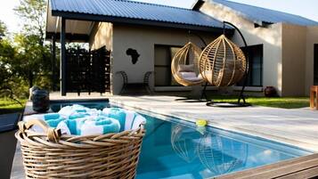 Una piscina al aire libre, sillones reclinables de piscina