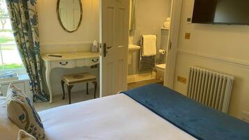 A hotel room with a bed, a vanity with a mirror, a toilet, and a television.