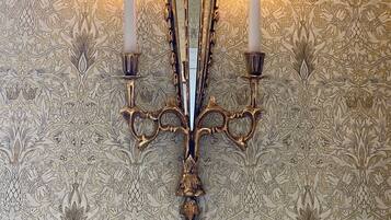 Un candelabro de pared con tres velas, sobre un papel tapiz estampado.