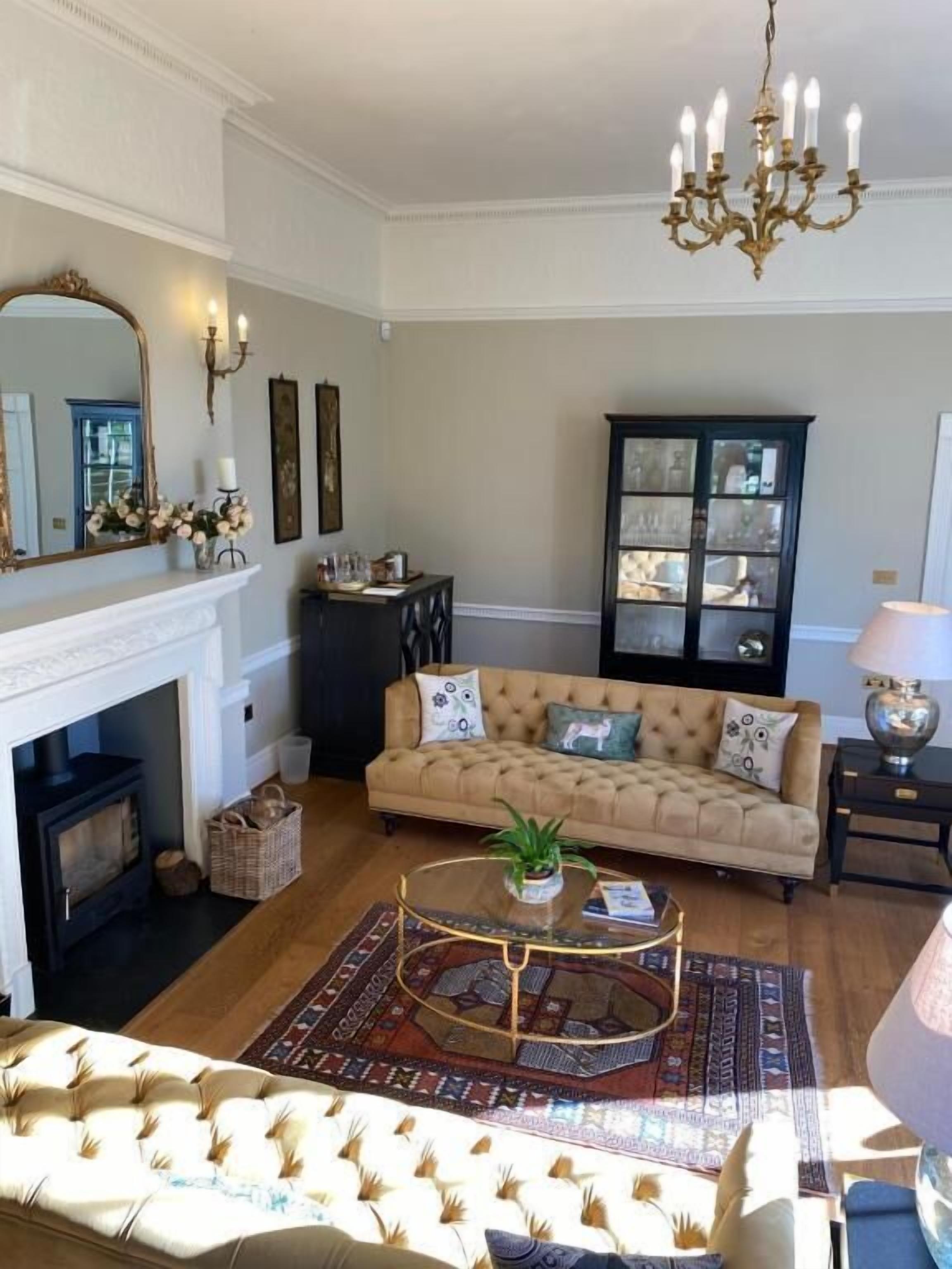 Una sala de estar con chimenea, sofá, mesa de centro y candelabro.