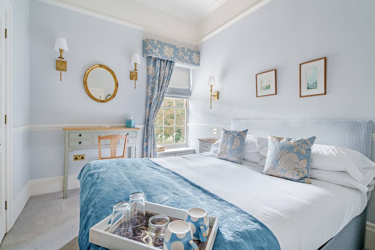 A bedroom with a bed, bedside tables, a dresser, and a window with curtains.