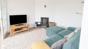 A living room with a television, sofa, and fireplace. - Awelfryn (Ty Croes)
