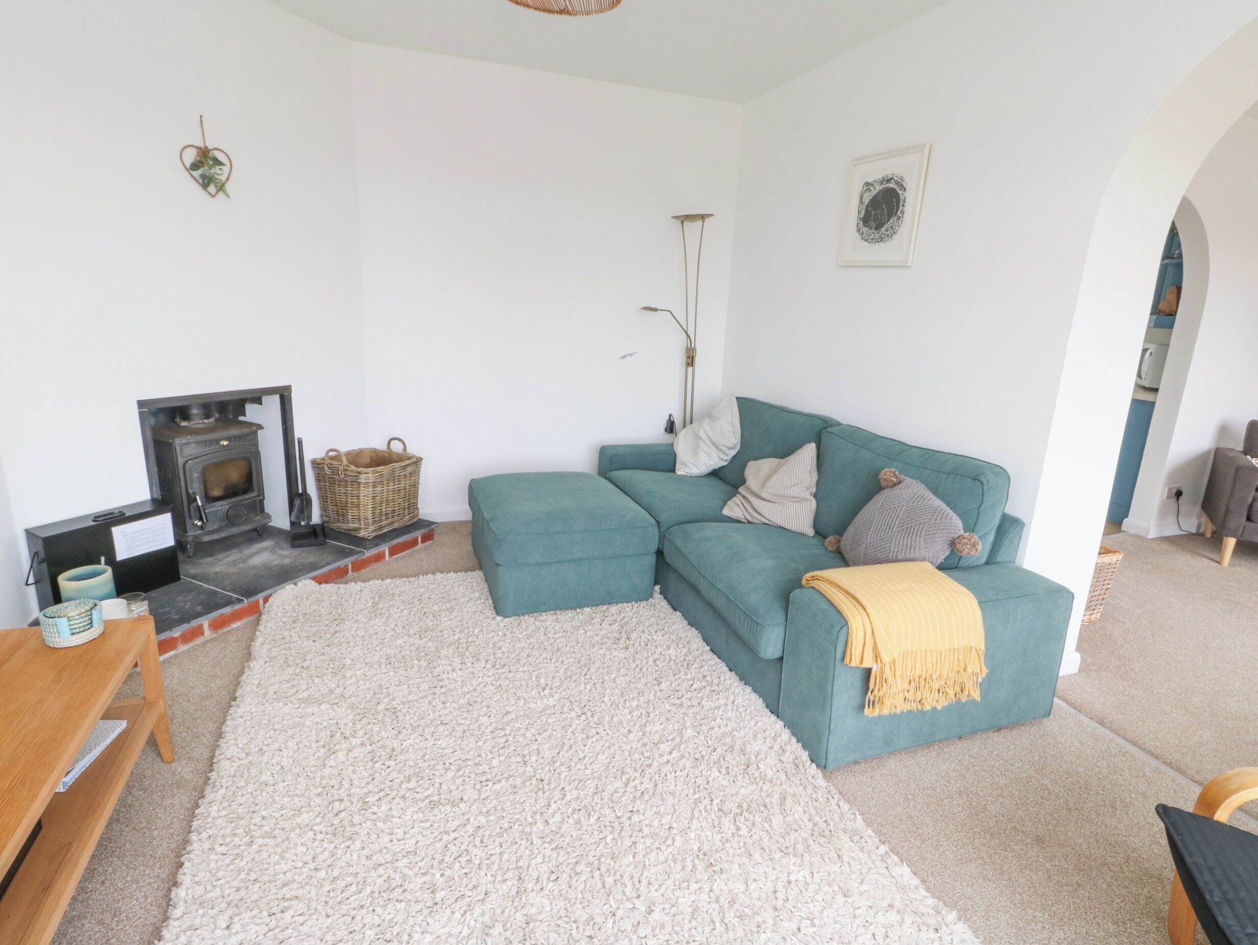 Una sala acogedora con un sofá color turquesa, un alfombra mullida blanca, una chimenea y una mesa de madera.