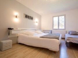Un dormitorio con una cama grande, una cama más pequeña, una mesita de noche, un radiador y una ventana.