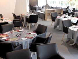 Un restaurante con mesas redondas, sillas negras y un diseño interior moderno.