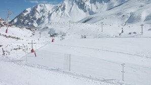 Een met sneeuw bedekte piste met skiliften en een berg op de achtergrond.