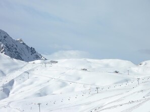 Pendiente nevada de una montaña con telesillas y cielo despejado.