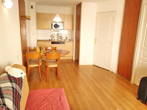 Espaço compacto com área de refeições, cozinha compacta e porta que dá acesso a outro quarto.