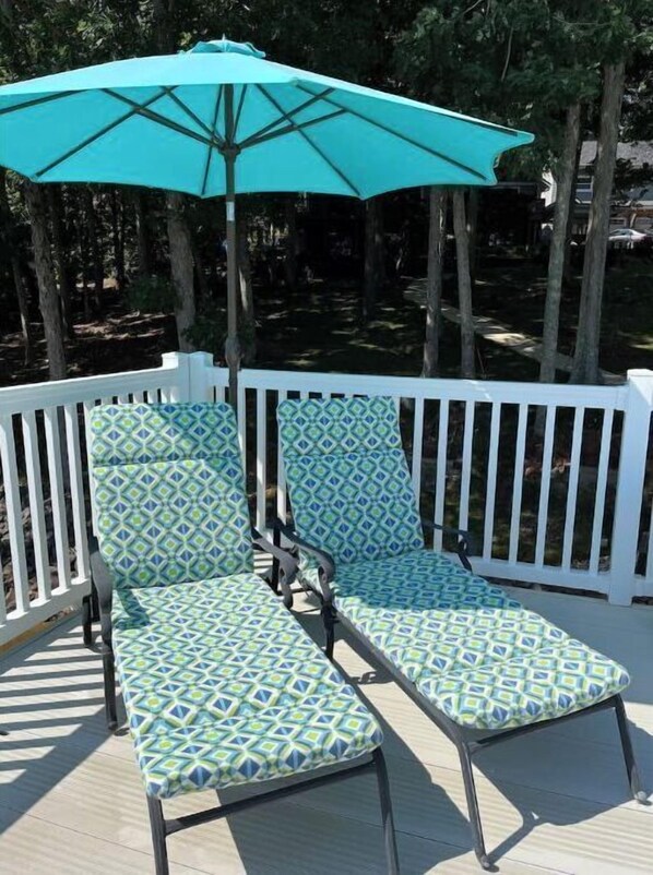 Una terraza con dos sillones de descanso y un paraguas turquesa.