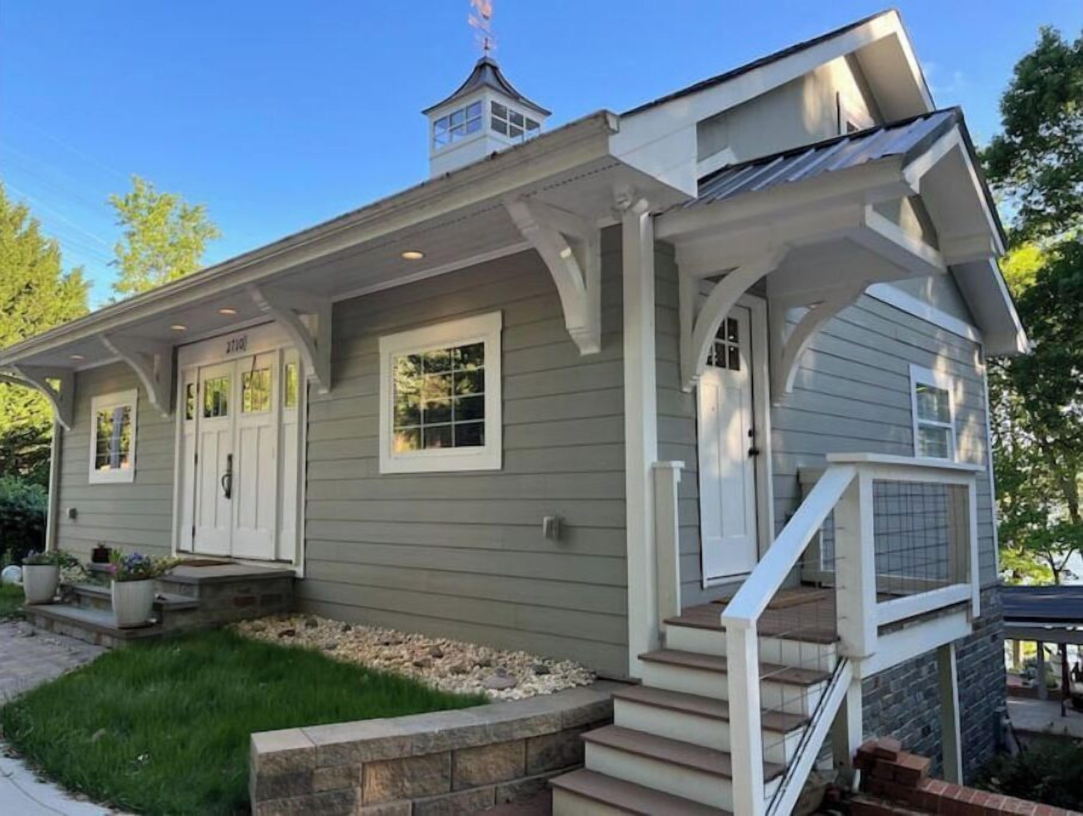A single-story house with a front porch, a small attached garage, and a chimney.