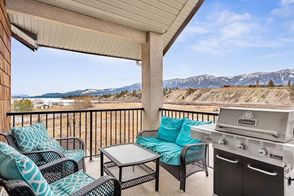 Un porche techado con mobiliario exterior, una parrilla y vistas a las montañas.