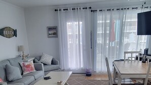 A living room with a sofa, a coffee table, and a dining area with a table and chairs.