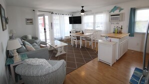 A compact living space with a sofa, dining table, chairs, a TV, and a kitchenette.