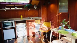 Une cuisine compacte aux murs en bois, dotée d’un four encastré, d’un évier et d’un petit réfrigérateur.