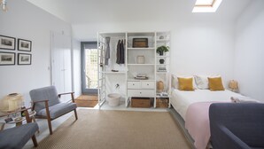 A modern bedroom with a bed, two chairs, a small table, a bedside lamp, and a window with a view of the outside. - Gardener's Cottage with Stunning Views (Rowlands Gill)