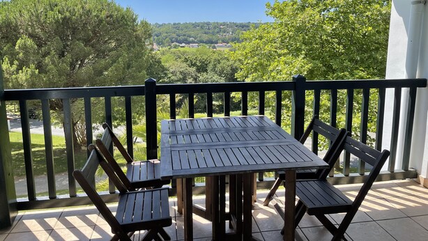 Eine überdachte Terrasse im Freien mit Tisch und Stühlen, mit Blick auf eine reizvolle Landschaft.