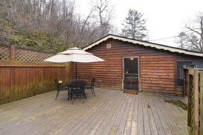 A wooden cabin with a deck, a table with chairs, and a large umbrella.