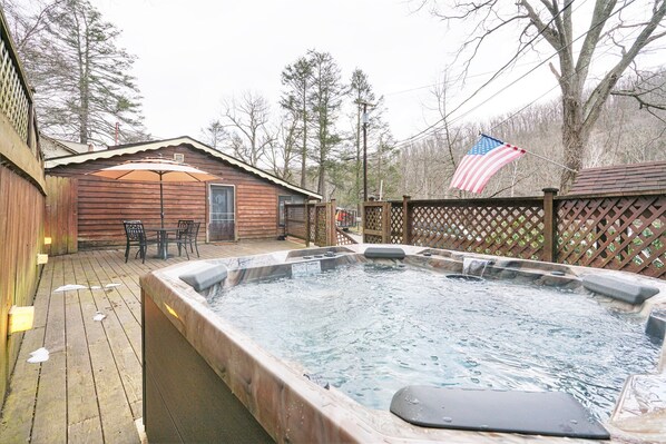 A wooden cabin with a hot tub and outdoor seating area.