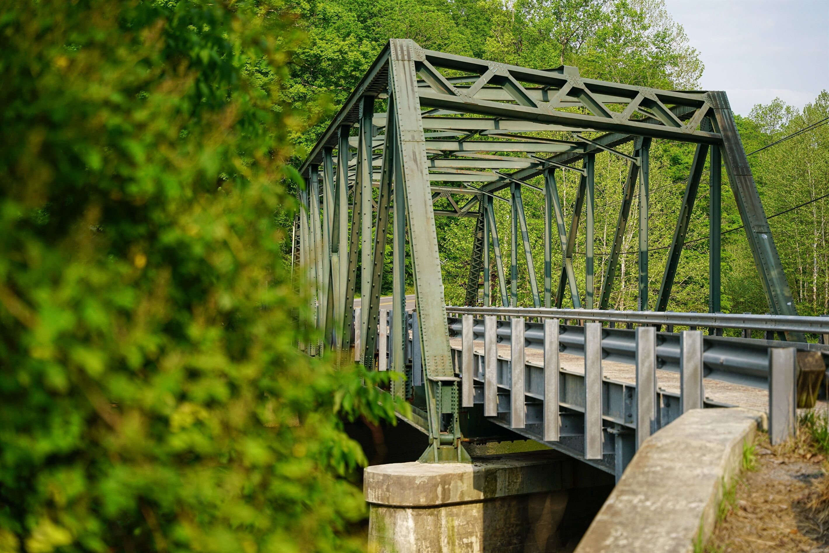 A steel truss bridge with a concrete walkway and guardrails.