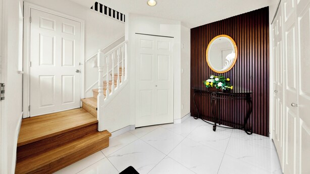 A staircase leading to a landing with a white door, a round mirror on a console table, and a potted plant. - Newly Renovated Home Heart of Vancouver Near YVR, Skytrain, Downtown (AC) (Vancouver)