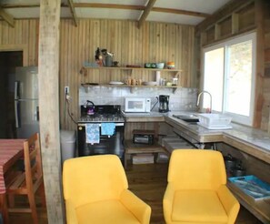 Cozy cabin kitchen with a refrigerator, microwave, and coffee maker, perfect for preparing meals and dining in.