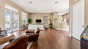 A spacious living room with a white sofa, leather chairs, and a flat-screen TV.