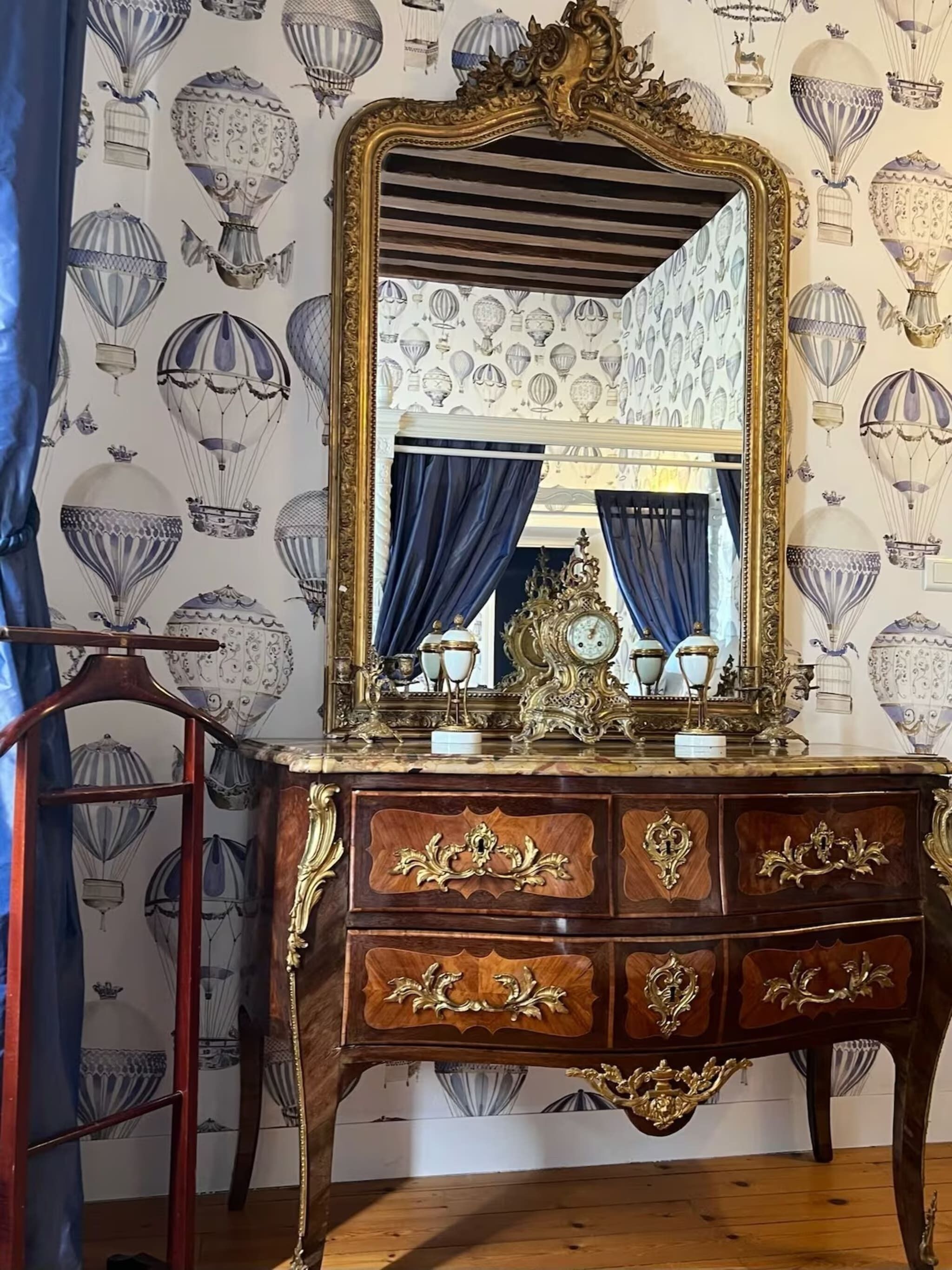 Un comò di legno antico con decorazioni in oro elaborate e un grande specchio.
