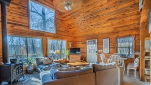 A cozy cabin interior with a wooden interior, a sofa, a television, and a fireplace. - Serenity Wood- The place for daytime outdoor adventures & cozy nights  (Blue Ridge)