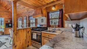 A wooden cabin kitchen with a stove, sink, and cabinets. - Serenity Wood- The place for daytime outdoor adventures & cozy nights  (Blue Ridge)