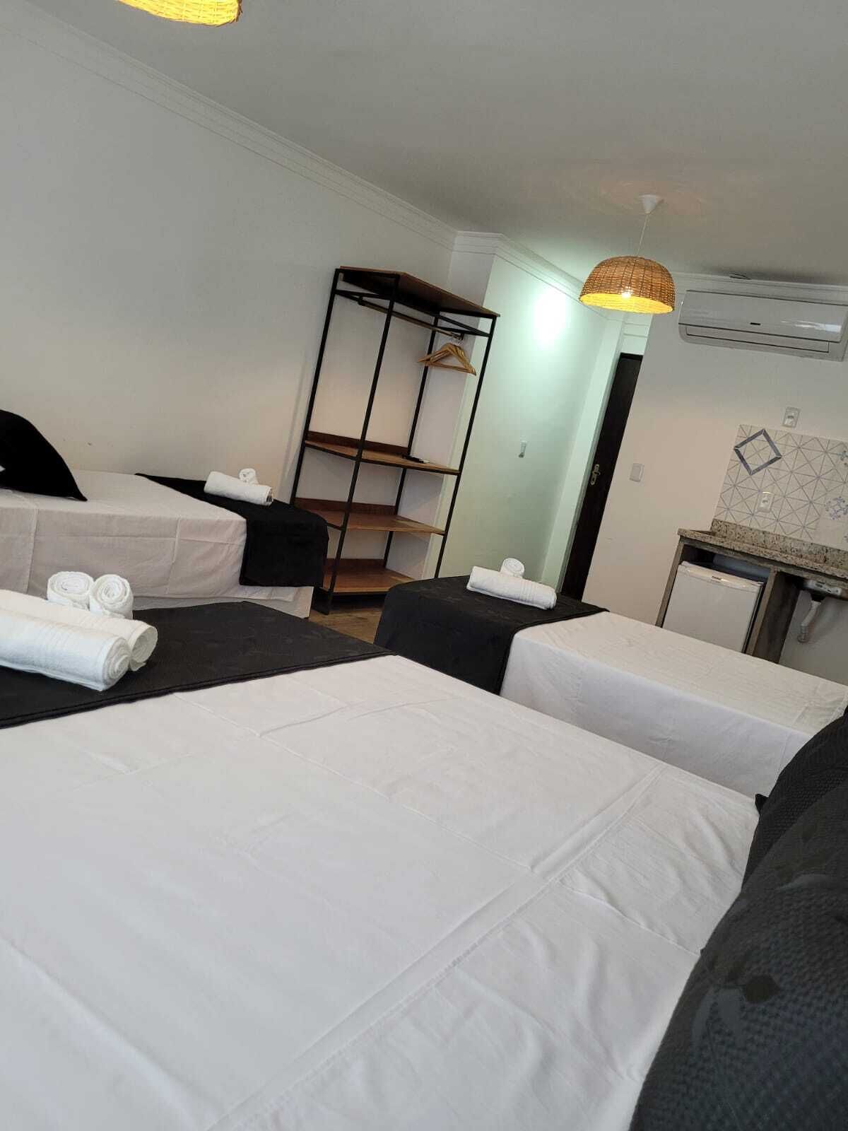 Ein Hotelzimmer mit zwei Betten, einem kleinen Schreibtisch, einem Kleiderschrank und einer Pendelleuchte.