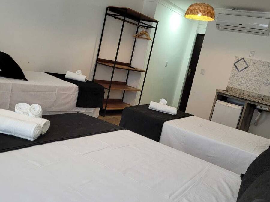 Ein Hotelzimmer mit zwei Betten, einem kleinen Schreibtisch, einem Kleiderschrank und einer Pendelleuchte.