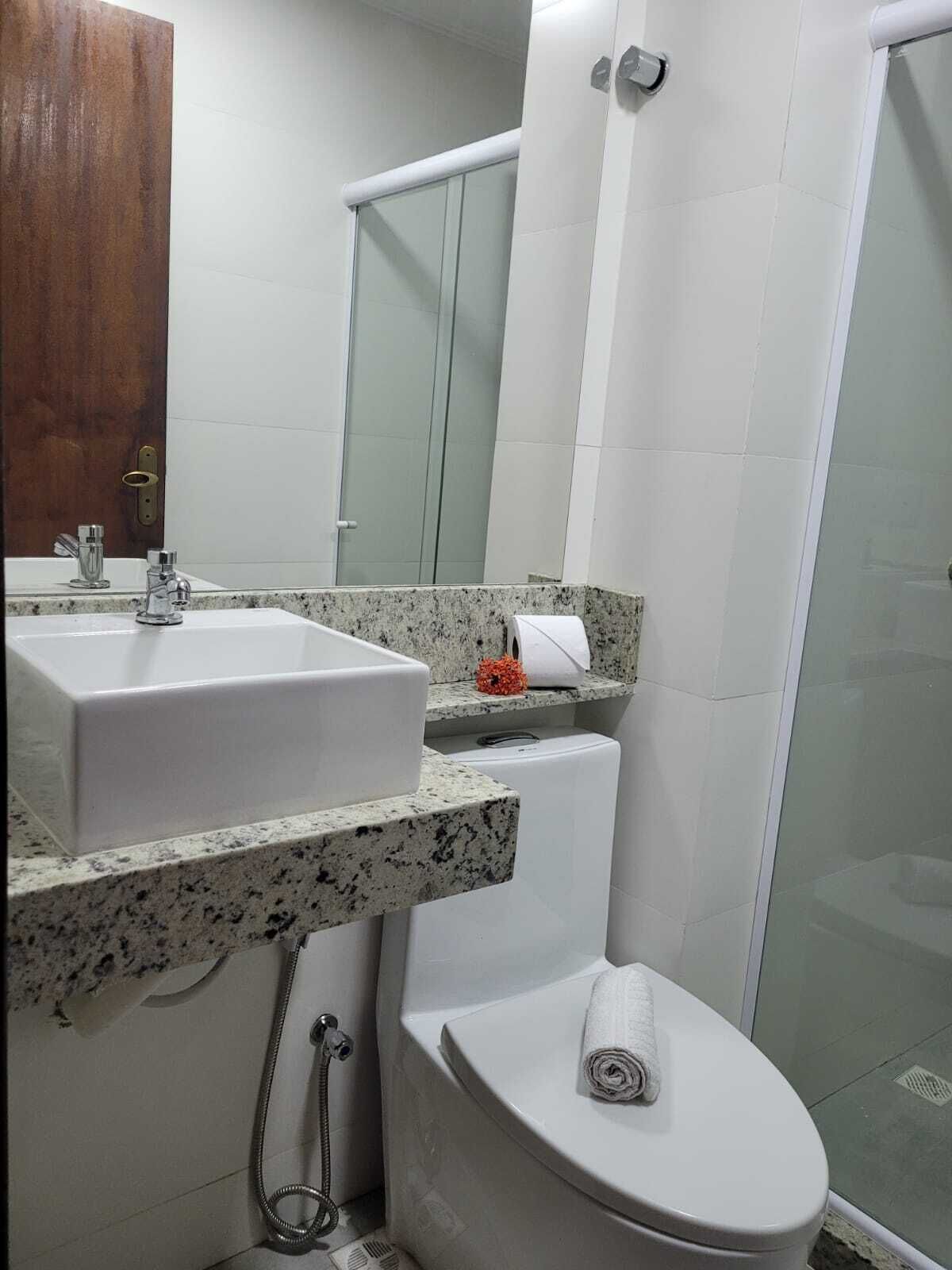 A bathroom with a sink, mirror, toilet, and shower.