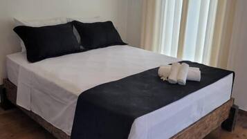A bed with white and black bedding, wooden legs, and a headboard.