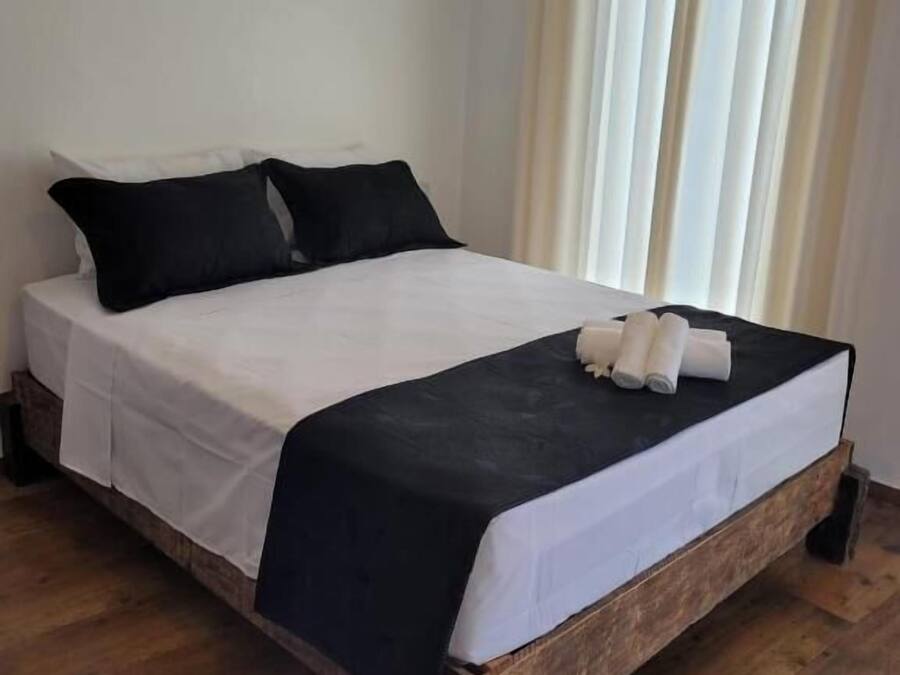 A bed with white and black bedding, wooden legs, and a headboard.